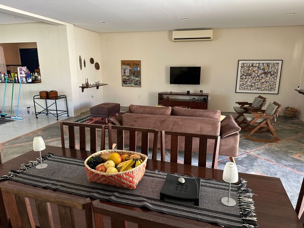 A living room with a sofa, a coffee table with fruit, a TV, and artwork on the walls.