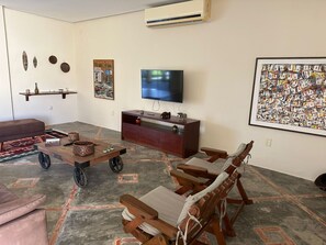 A living room with a TV, wooden furniture, and artwork on the walls.