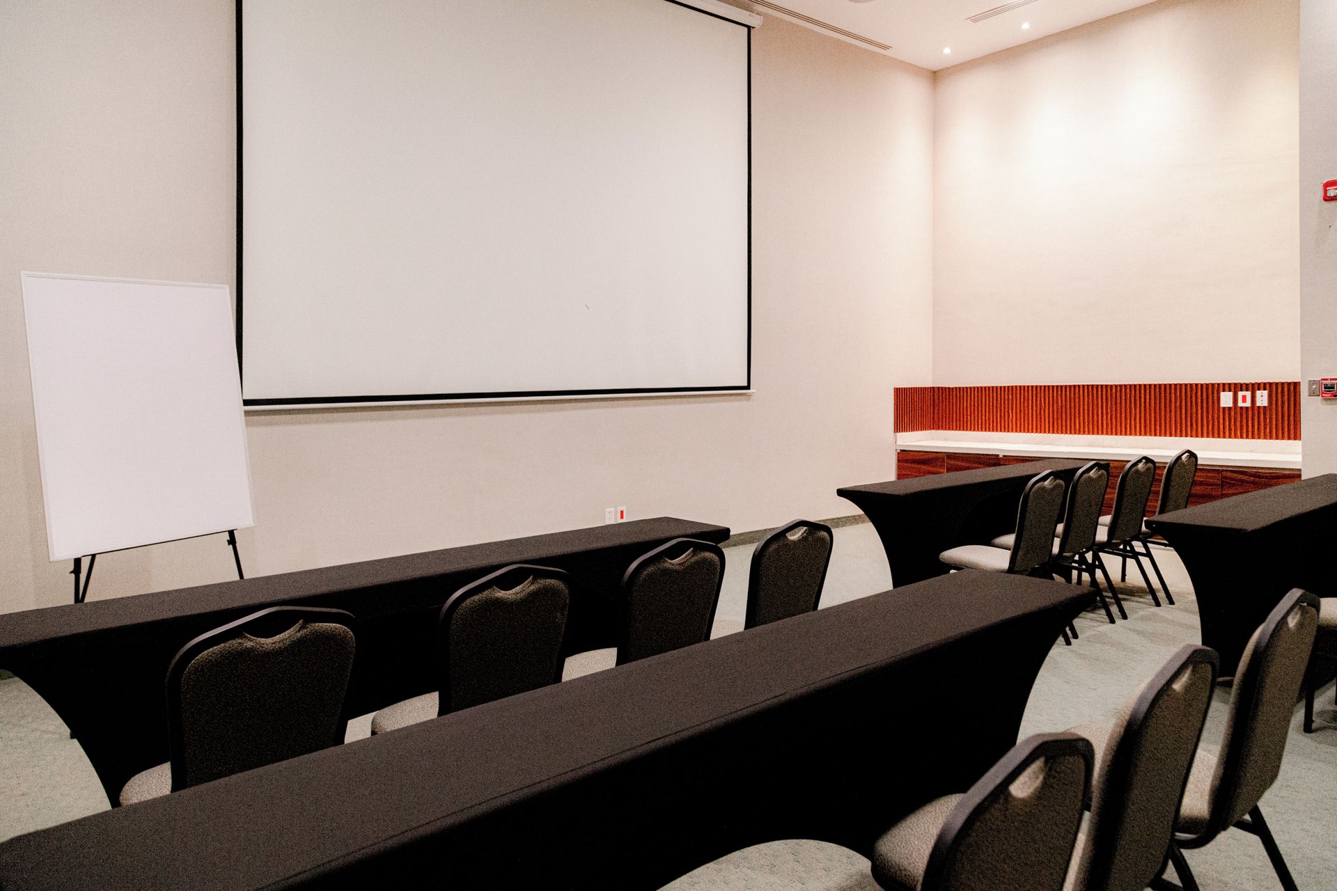 A conference room with a whiteboard, multiple tables, and chairs.