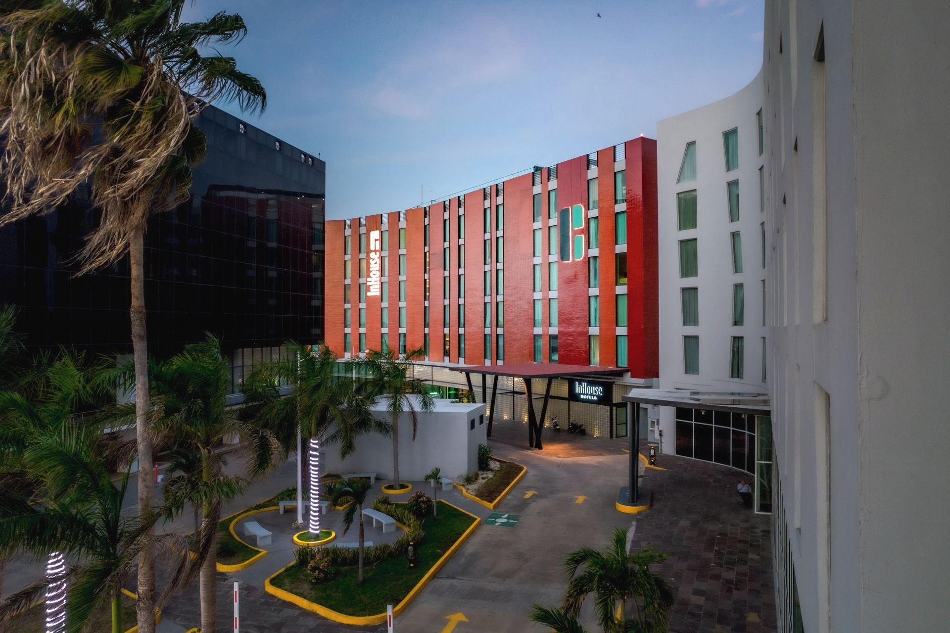 Un hotel con fachada moderna, un atrio central y un patio ajardinado.