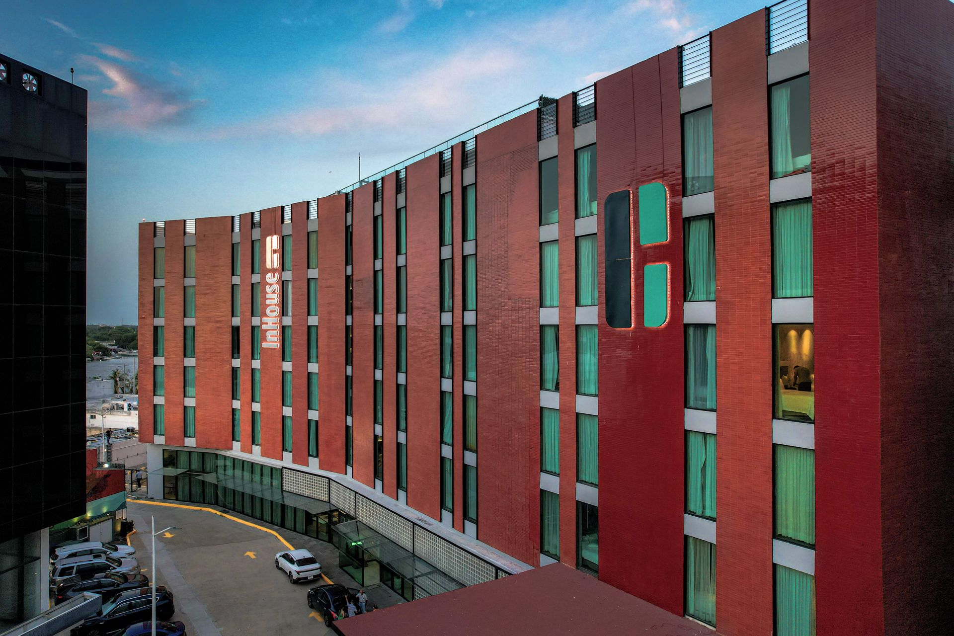 A modern hotel with a curved facade, large windows, and a prominent logo.