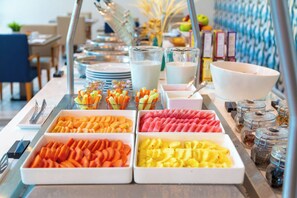Un bufé con diversas opciones de comida, incluyendo frutas y verduras.