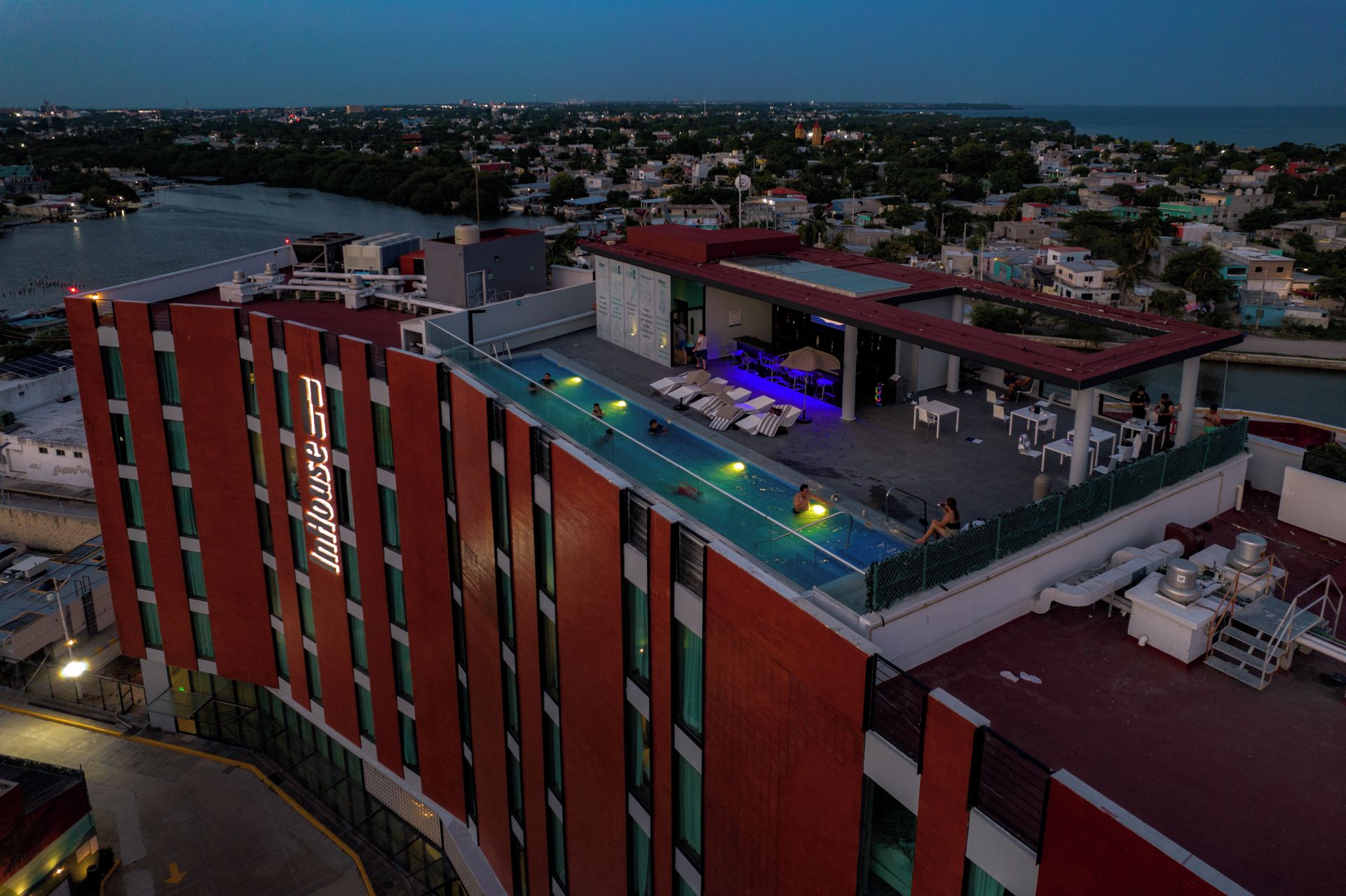 Una terraza de hotel con piscina, sillones de descanso y vistas a la ciudad.