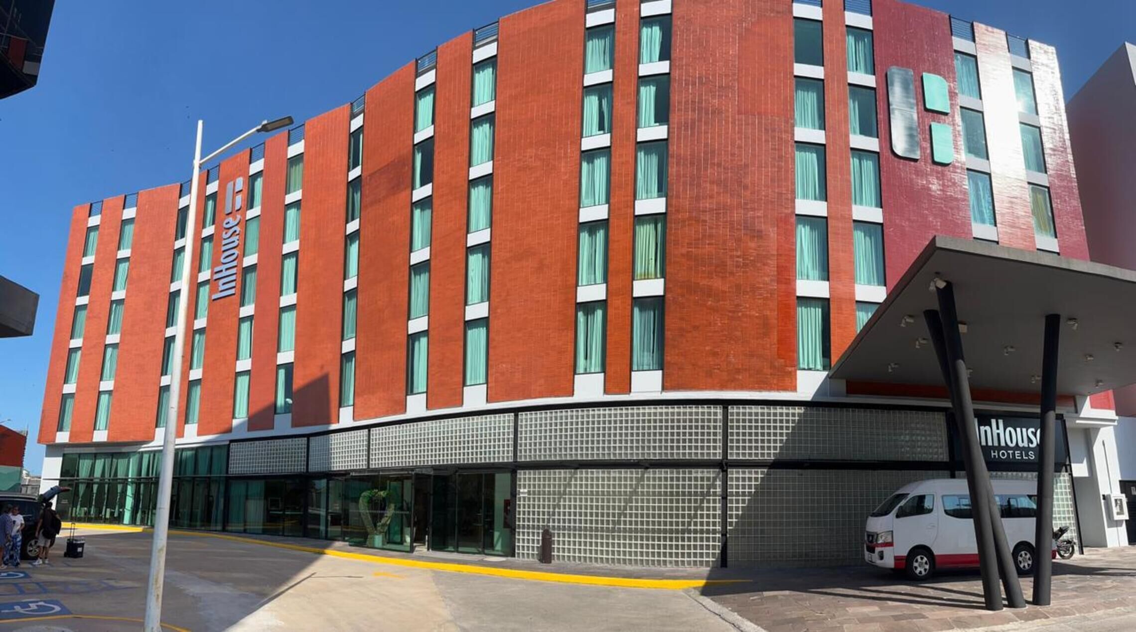 A modern hotel with a red facade, large windows, and a covered entrance.