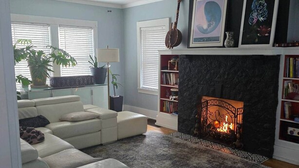 Una sala de estar con chimenea, un sofá, una mesa de centro y una estantería.