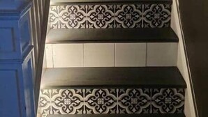 Una escalera con baldosas estampadas y barandilla.