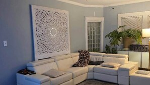 Una sala de estar con un sofá modular, un adorno de pared, una planta en maceta y una lámpara.