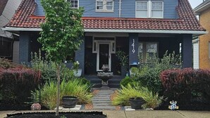 Una casa de dos pisos con techo de tejas rojas y fachada azul.