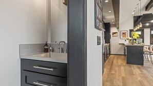 Una cocina moderna con un lavaplatos empotrado, piso de madera y una zona de bar con taburetes.