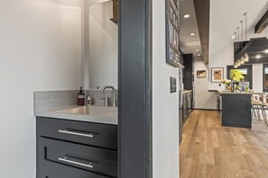 Eine moderne Küche mit eingebautem Spülbecken, Holzboden und einer Bar mit Sitzhocker.