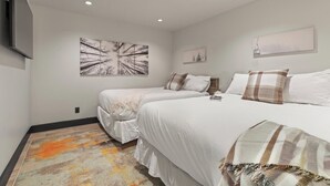 Habitación de hotel con dos camas, televisión y obras de arte en las paredes.
