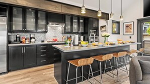Una cocina moderna con una isla central, taburetes de bar y una zona de comedor.