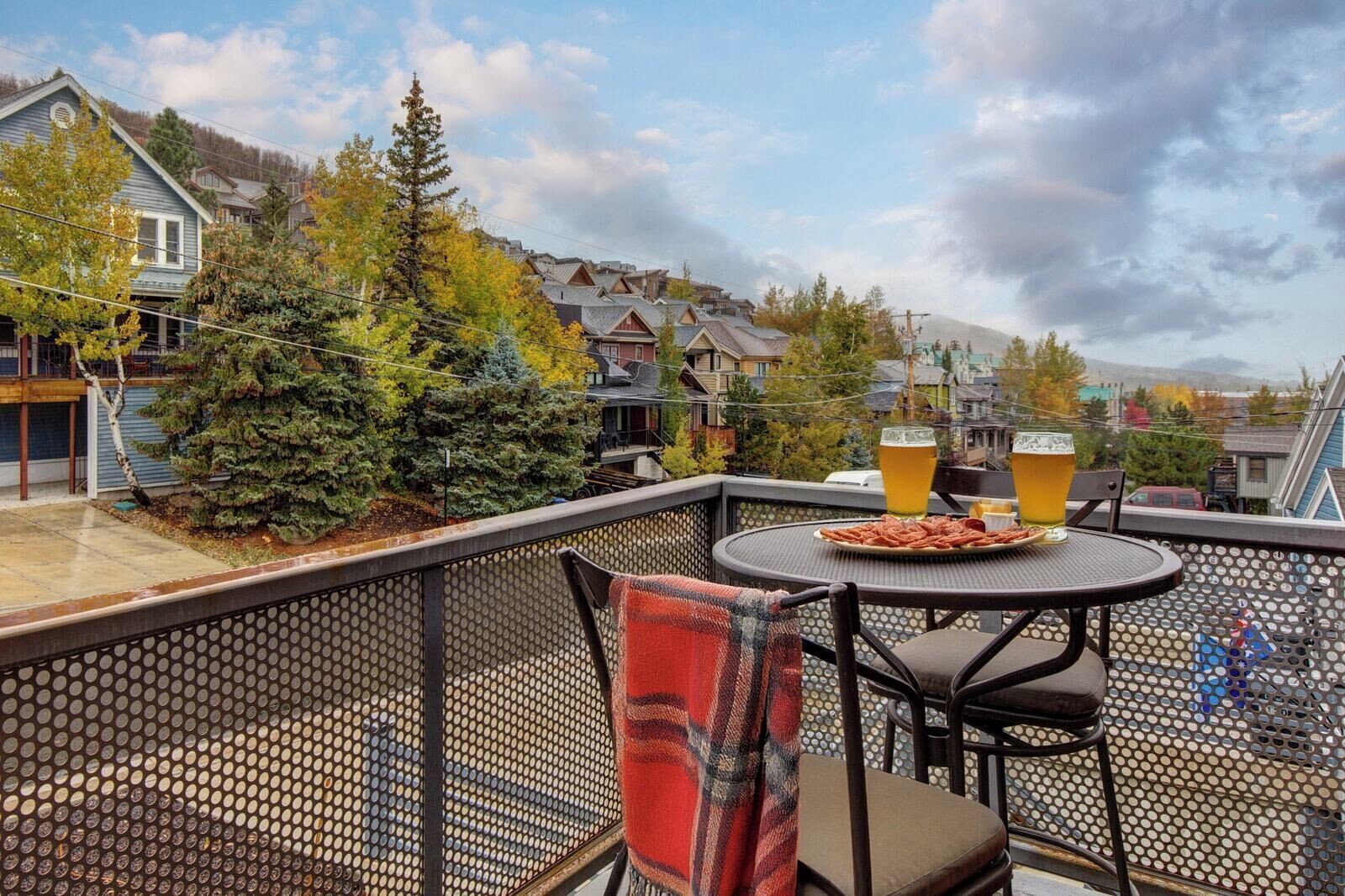 A balcony with a table, chairs, and a glass of beer.