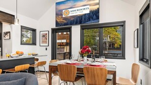 Un comedor moderno con un ventanal grande, una mesa lista para cuatro comensales y un cartel de KBM Resorts.