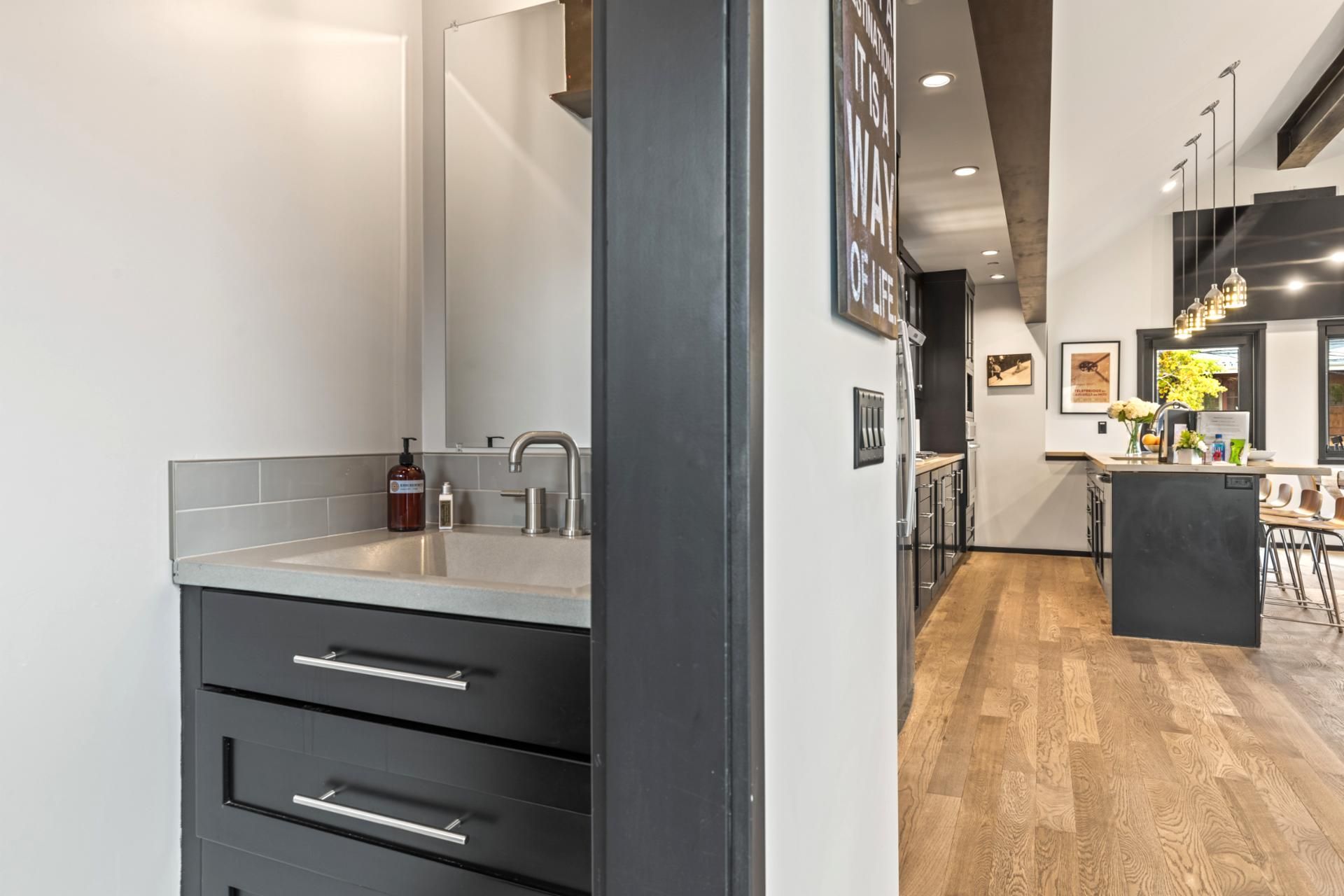 A modern kitchen with a wooden floor, a built-in sink, and a dark-colored cabinet.