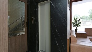 A modern elevator with a marble wall, a wooden door, and a glass panel. - Townhouse Reti Bus Terminal Udaipur (Udaipur)
