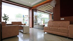 A modern lobby with a marble floor, two sofas, a coffee table, and a large window offering a view of the street. - Townhouse Reti Bus Terminal Udaipur (Udaipur)