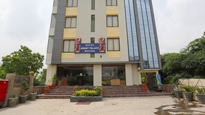 A hotel with a Pepsi sign, a staircase leading to the entrance, and a large glass building on the right. - Townhouse Reti Bus Terminal Udaipur (Udaipur)