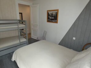 Een slaapkamer met stapelbedden, een stoel en een lijst aan de muur.