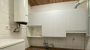 Une cuisine compacte avec des meubles blancs, un plan de travail en granit, un lave-linge encastré et un chauffe-eau.