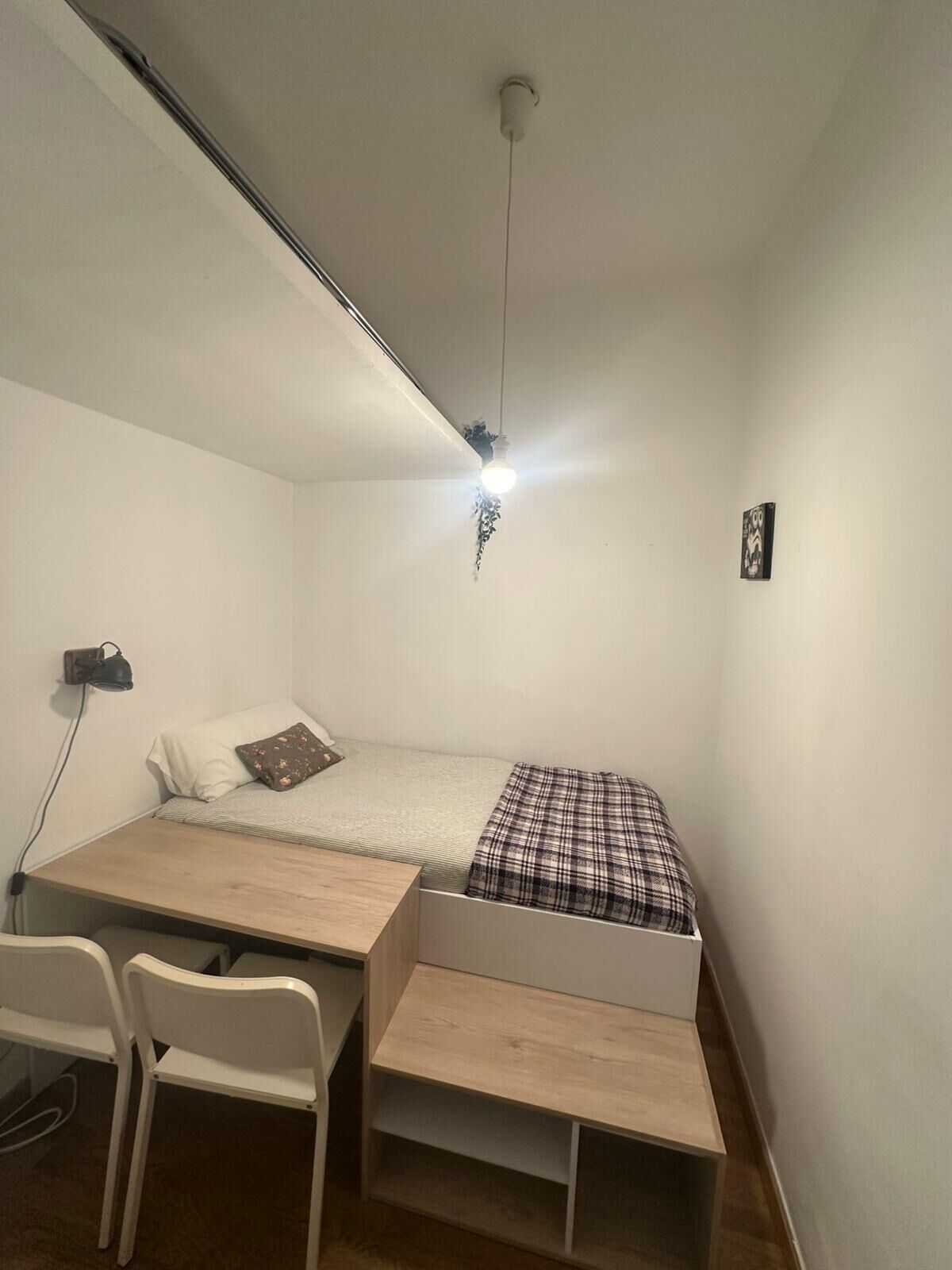 Una habitación pequeña y funcional con cama, escritorio y silla.