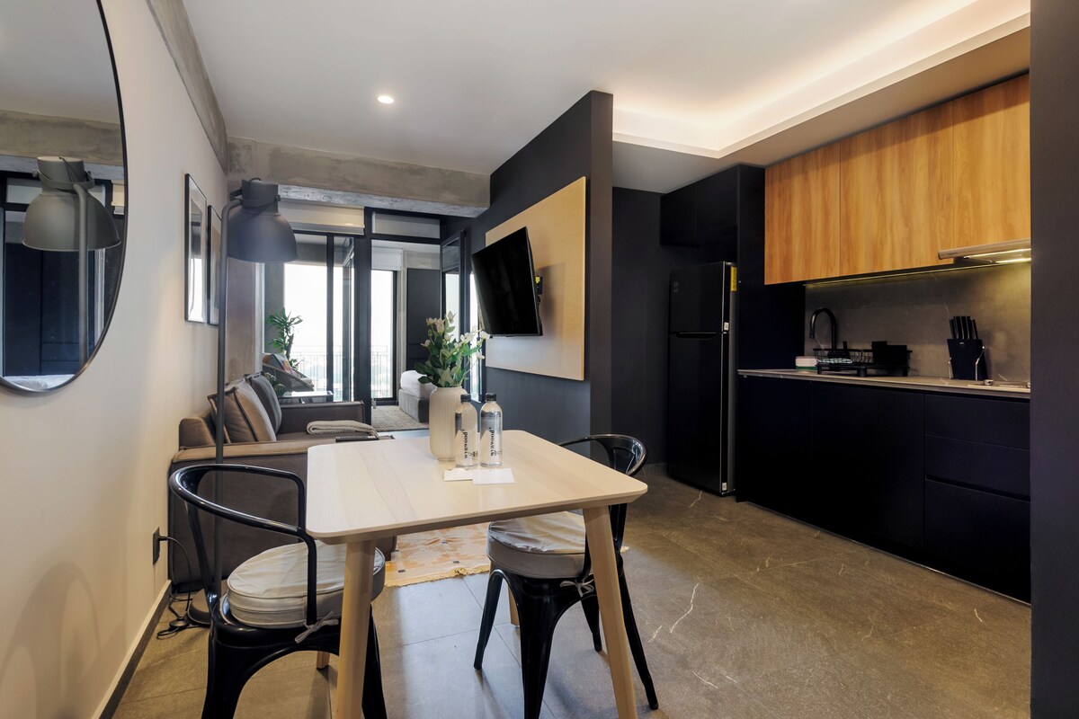 A modern kitchen with a built-in oven, a refrigerator, and a dining area with a table and chairs.