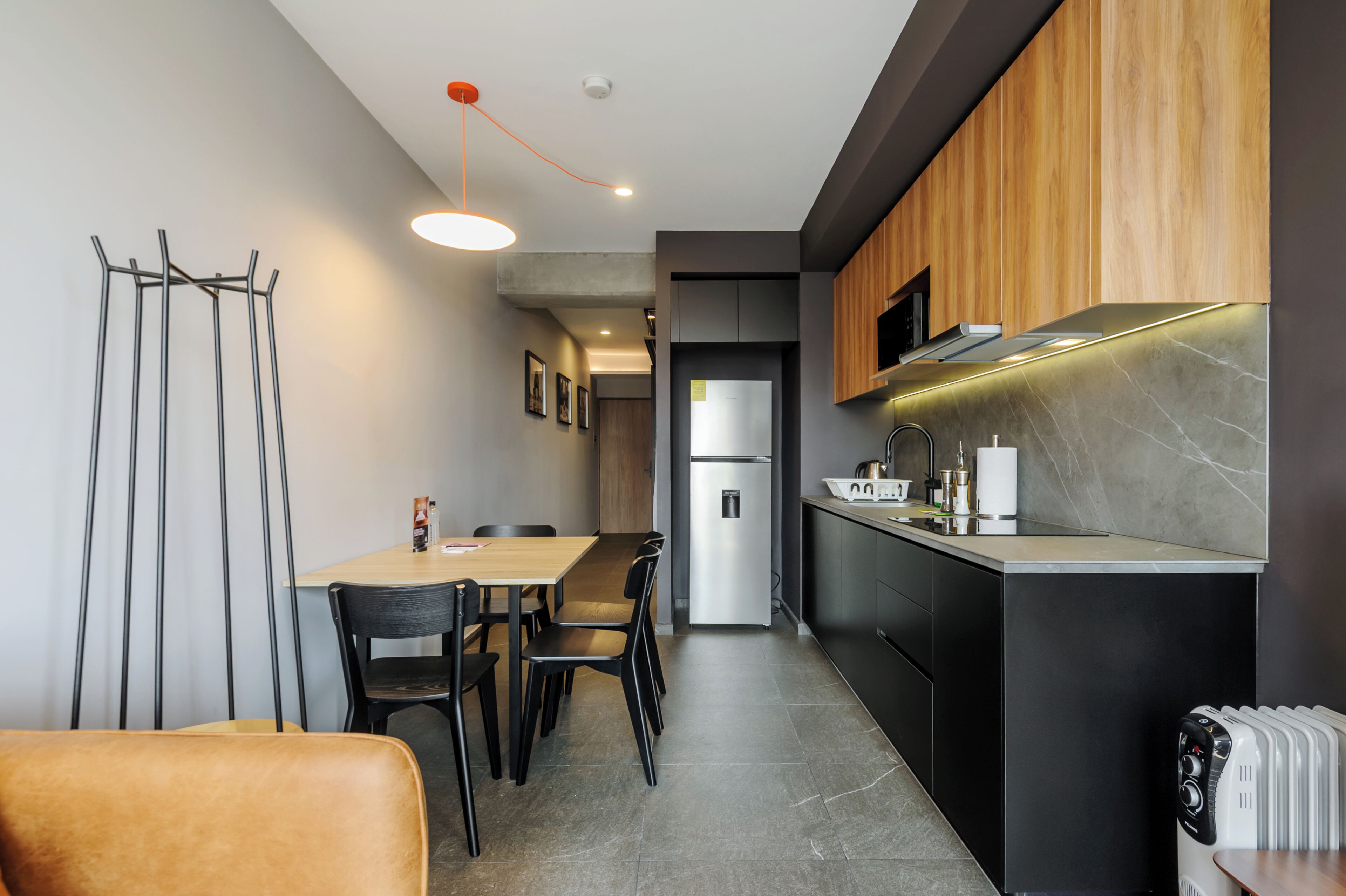 A modern kitchen with a dining area, featuring a central island, built-in appliances, and a pendant light.