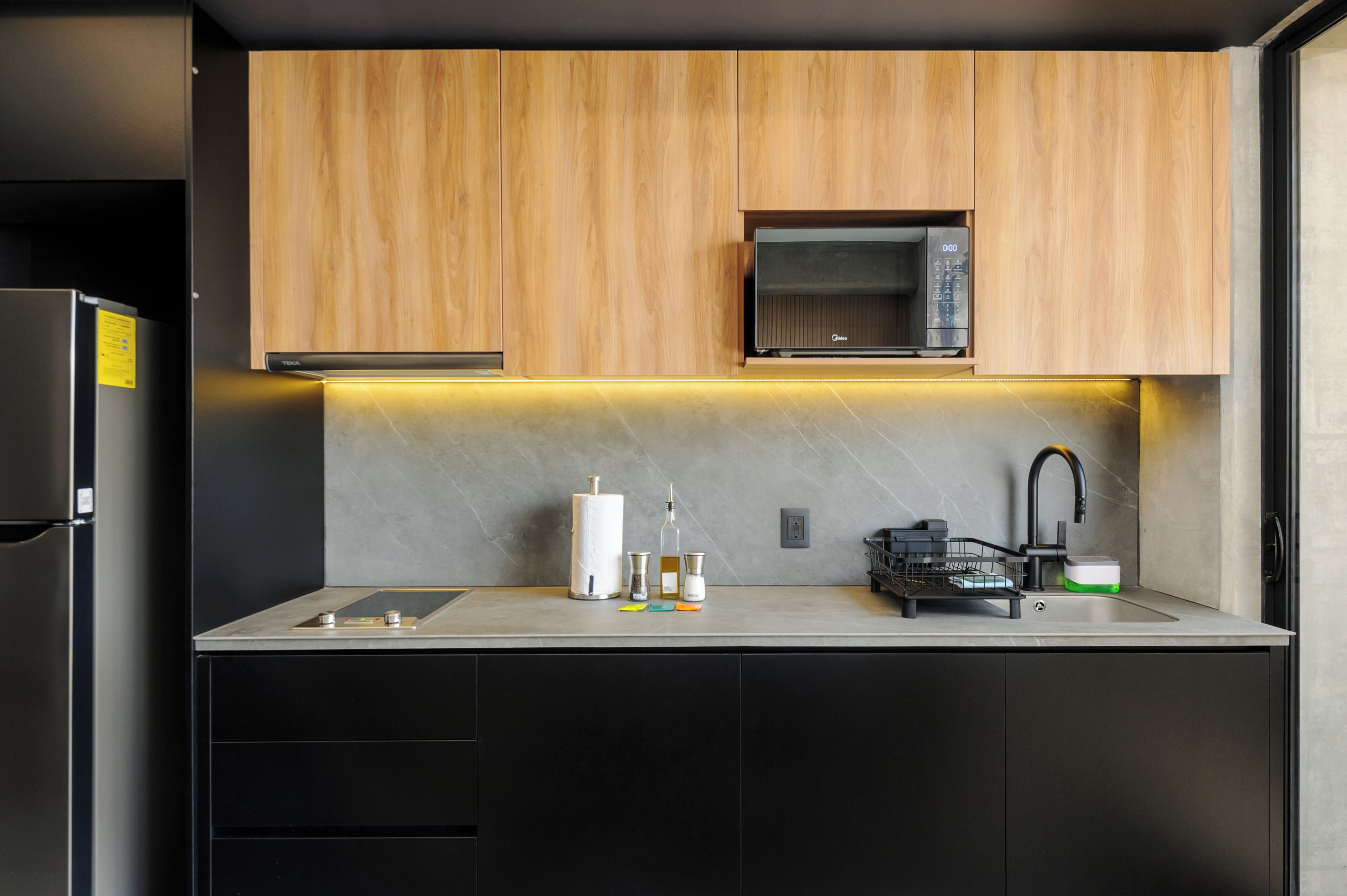 Une cuisine moderne avec des meubles en bois, un four à micro-ondes, un évier et un lave-vaisselle.