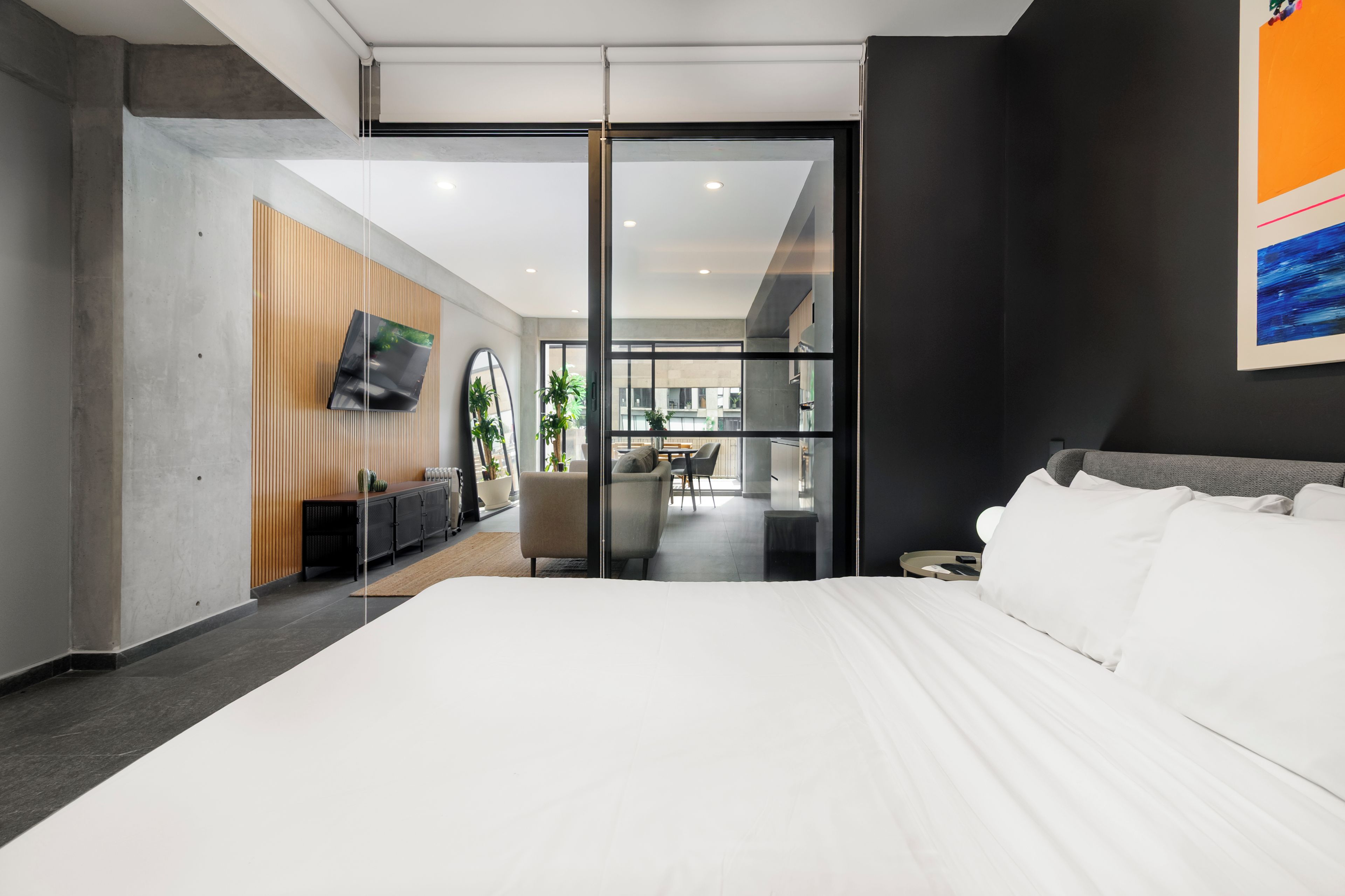 Een moderne hotelkamer met een groot bed, een bureau, een stoel en een televisie aan de muur.
