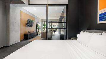 Een moderne hotelkamer met een groot bed, een bureau, een stoel en een televisie aan de muur.