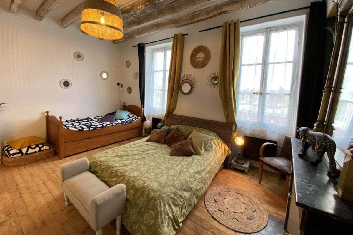 A cozy bedroom with a bed, a chair, a table, and a window with curtains.