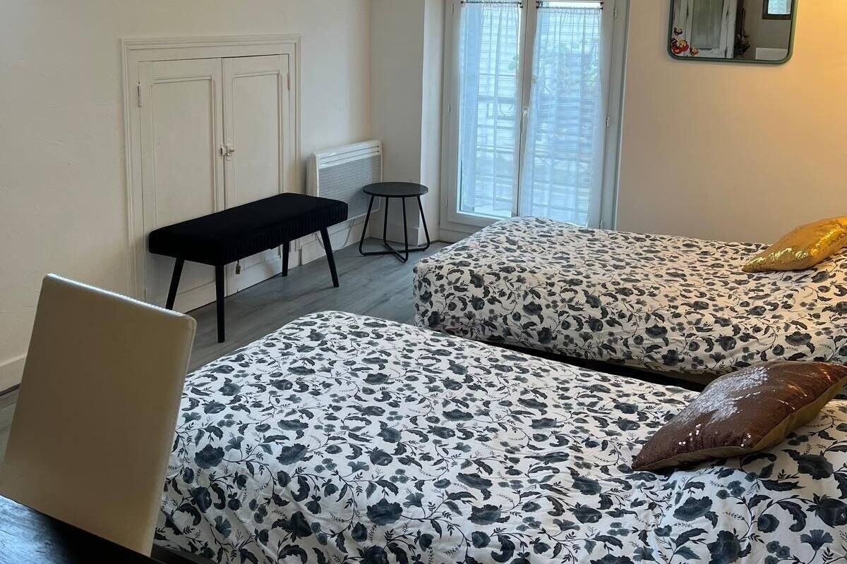 A bedroom with a skylight, a bed with floral bedding, a bench, and a desk.