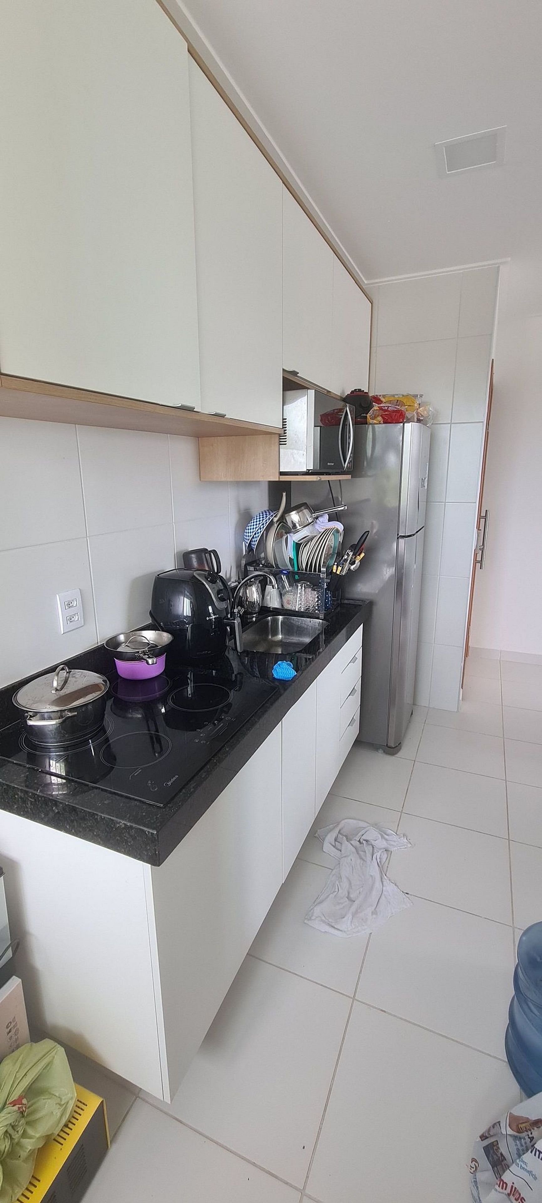 A kitchen with white cabinets, a black countertop, and a stainless steel refrigerator.