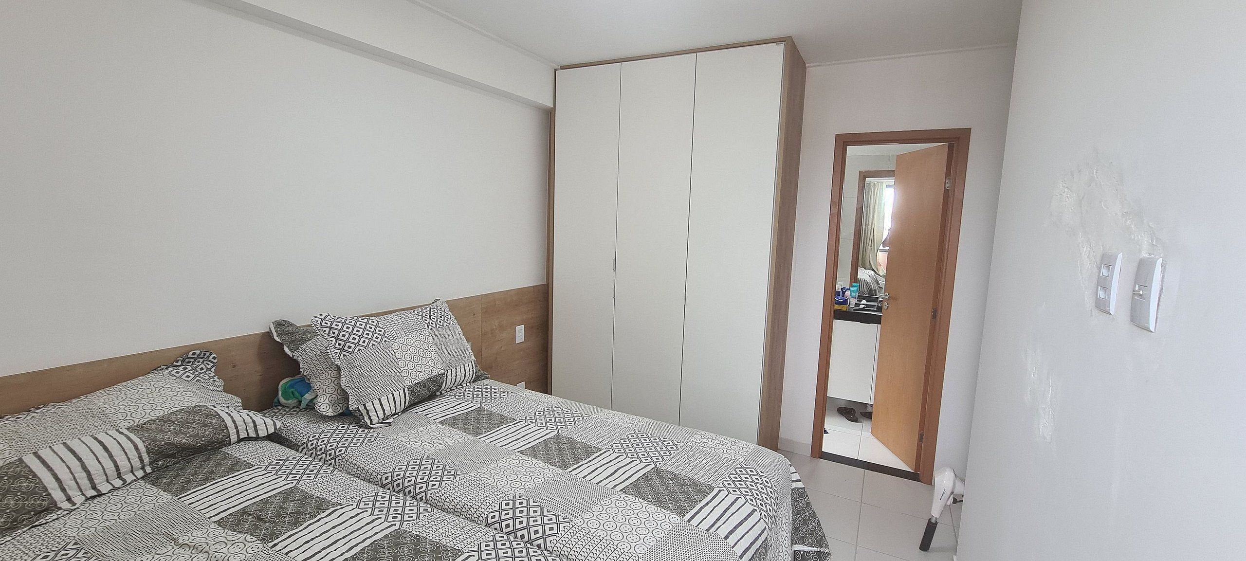 A bedroom with a bed, pillows, a wardrobe, and a mirror.