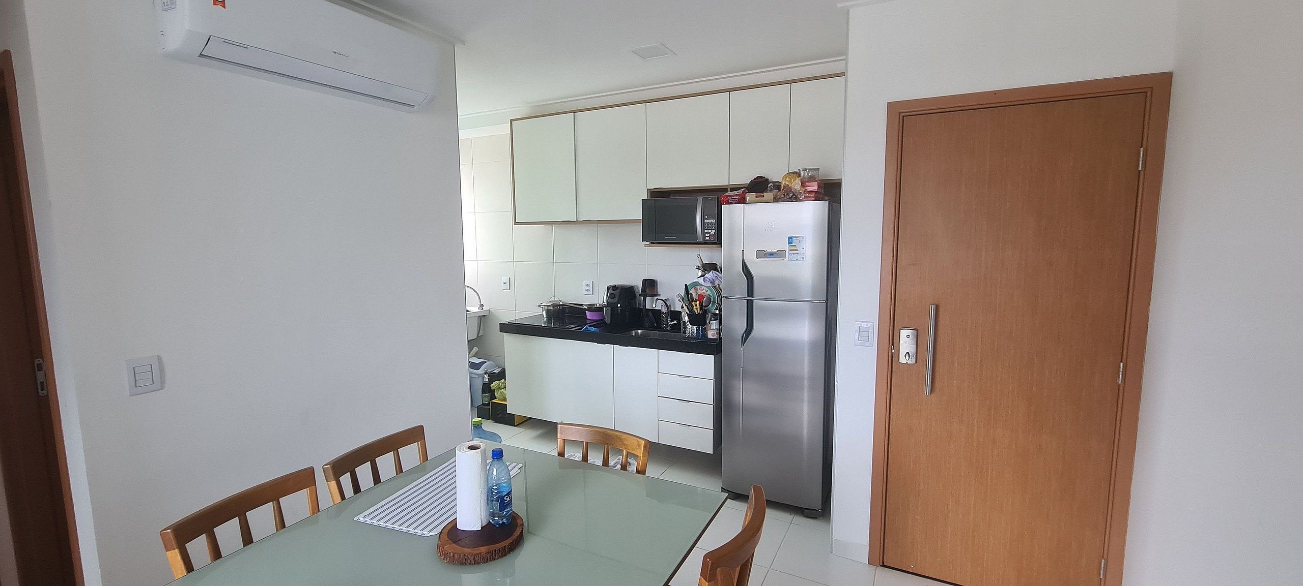 A compact kitchen with white cabinets, a stainless steel refrigerator, and a microwave.