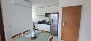 A compact kitchen with white cabinets, a stainless steel refrigerator, and a microwave. - Mana Beach Experience (Ipojuca)