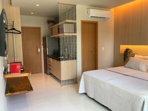 A bedroom with a bed, a kitchenette, and a sliding door. - Mana Beach Experience (Ipojuca)