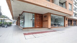 A modern building with a large glass entrance and a wooden door marked with the number 151. - Cozy 1-bedroom apartment in pleasant Providencia with AC (Providencia)