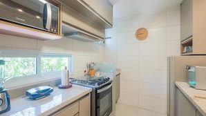 Une cuisine équipée d’une cuisinière à gaz, d’un four, d’un four à micro-ondes et d’une horloge murale.