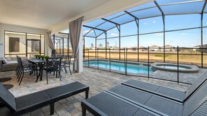 A covered outdoor area with a pool, seating, and a view of the surrounding landscape. - Dream 9BR Home - Game Room - Hot Tub - Sleeps 22! (Kissimmee)