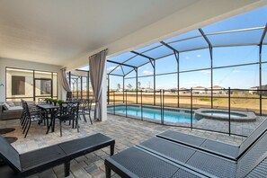 Ein überdachter Außenbereich mit Pool, Sitzgelegenheiten und Blick auf die umliegende Landschaft.