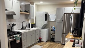 Una cocina moderna con armarios blancos, un refrigerador de acero inoxidable, un microondas y una estufa.