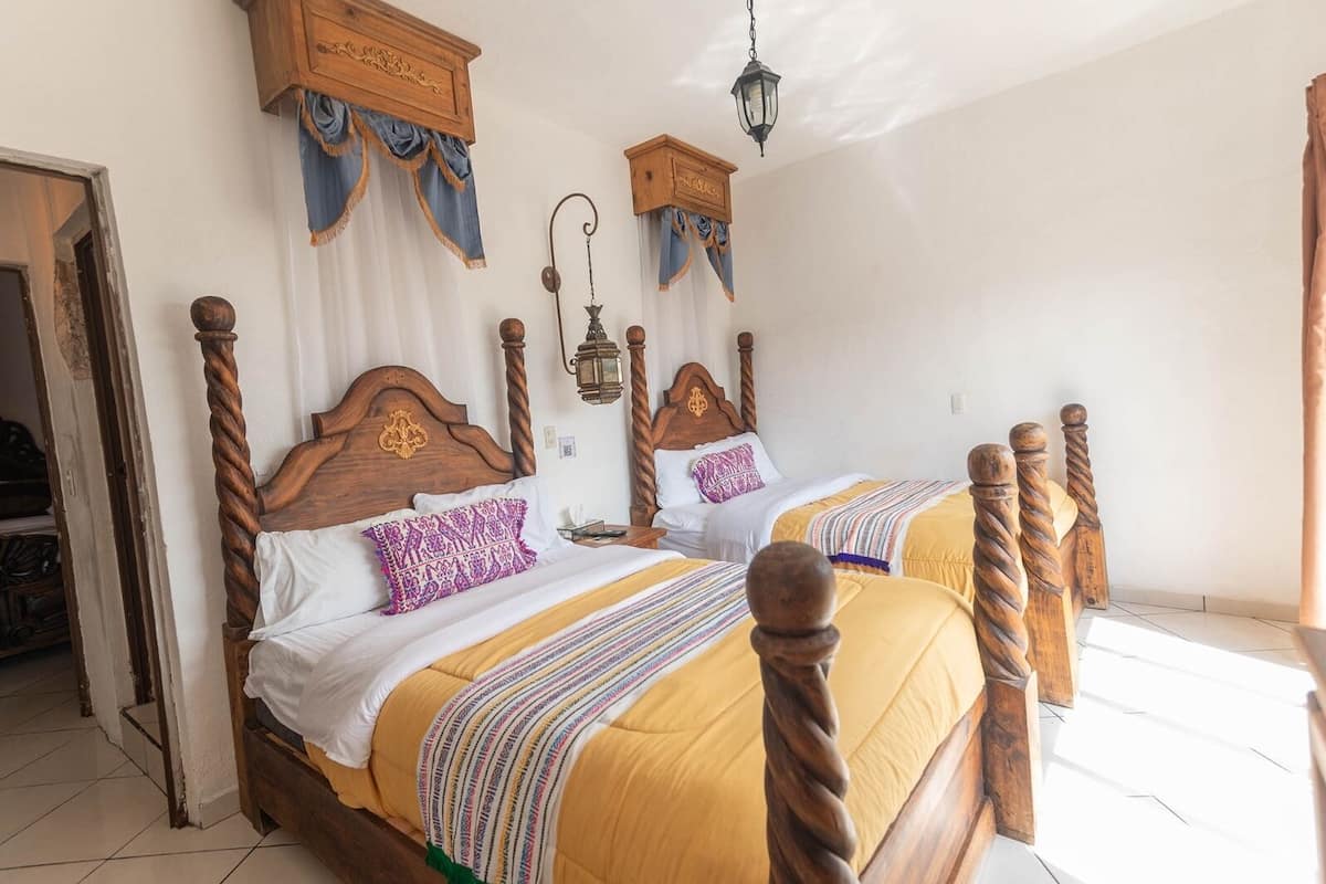 A room with two wooden beds, a hanging lantern, and a wooden cabinet.