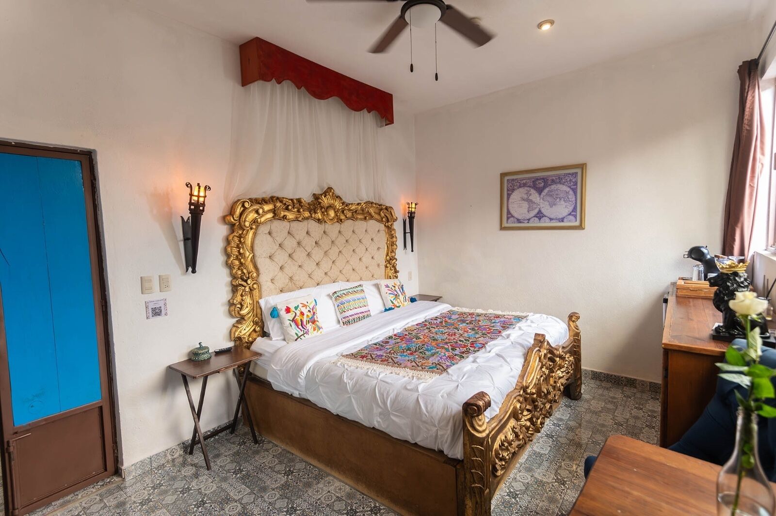 Un dormitorio con una cama grande, ventilador de techo, escritorio y una silla.