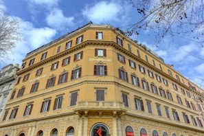 A corner building with multiple windows and a prominent clock. - Vatican | The House of Painting | Home and More (ROMA)