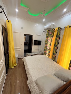 A bedroom with a bed, a TV, and a ceiling light.