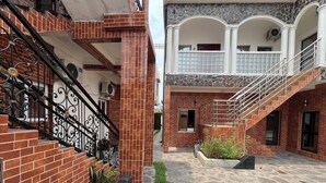 Un patio con muro de ladrillo, escalera de metal y suelo de piedra.