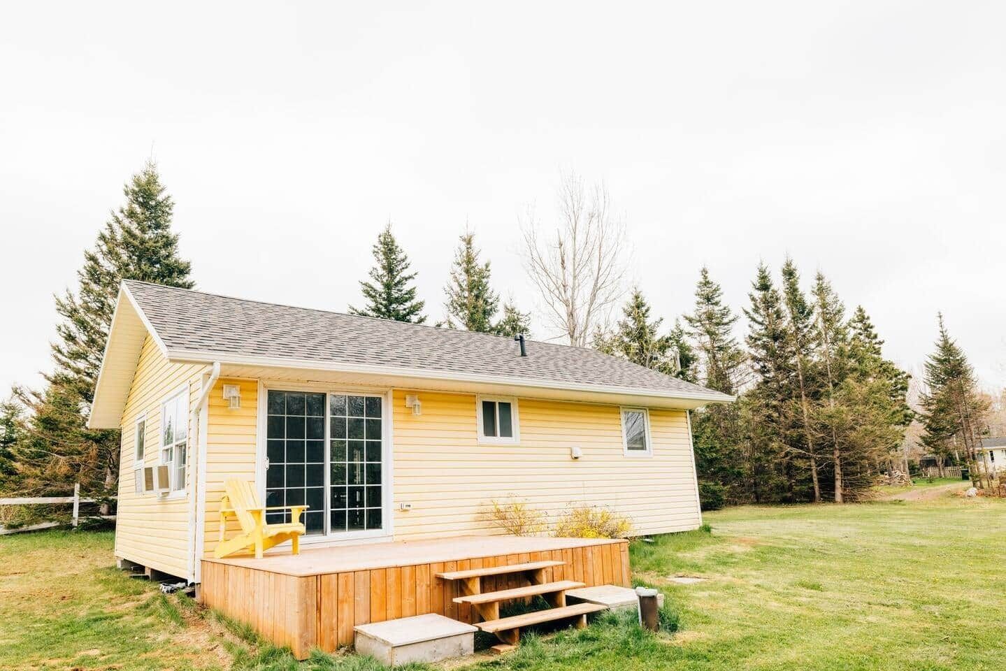 Une petite maison de plain-pied avec une terrasse en bois et une grande fenêtre.
