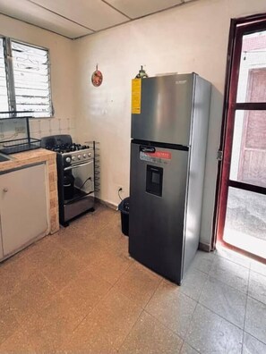 Una cocina con refrigerador, horno y estufa a gas.