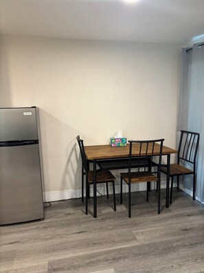 A compact kitchen with a refrigerator, a wooden dining table with four chairs, and a tissue box on the table. - Fully renovated a year ago, fully equipped, convenience, excellent location. (Pasadena)
